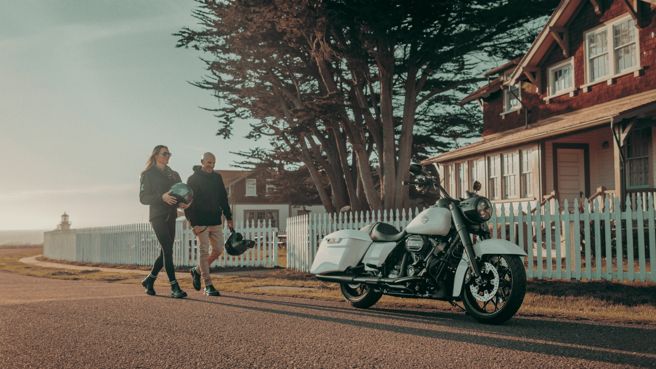 2025 Harley-Davidson Road King Special parked near classic cottage at sunset with riders nearby