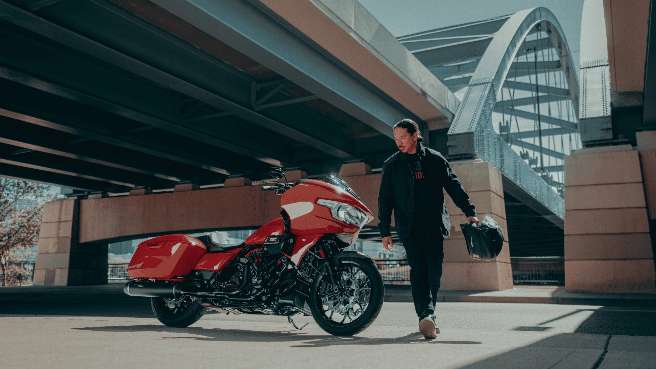 2025 Harley-Davidson CVO Road Glide ST near Sunrise, FL under a bridge with rider holding a helmet, showcasing bold performance design.