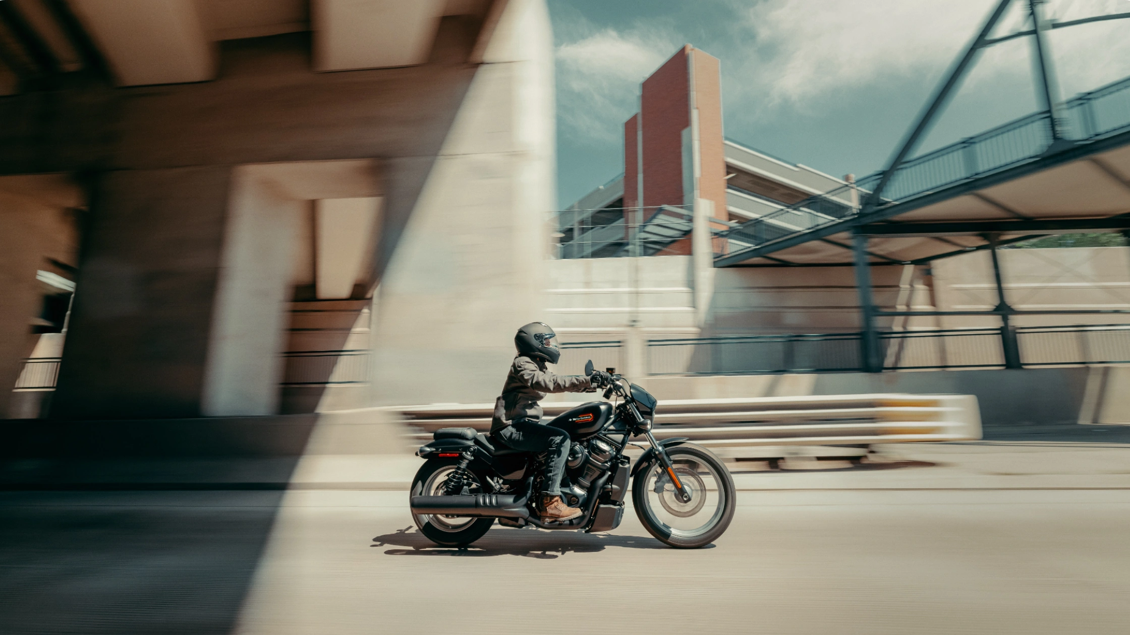 Rider on 2025 Harley-Davidson® Nightster® Special cruising under city overpass in motion blur.