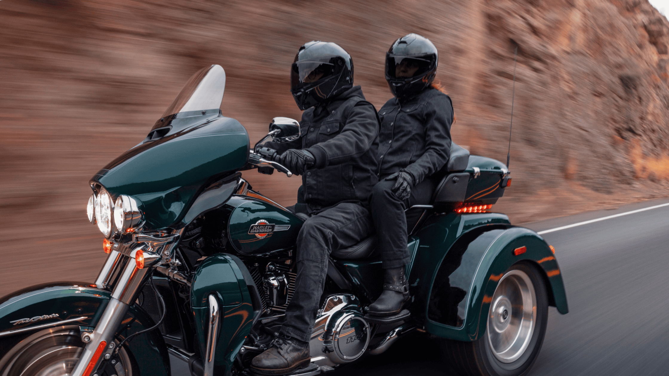 2025 Harley-Davidson Tri Glide Ultra touring trike with two riders cruising through canyon road