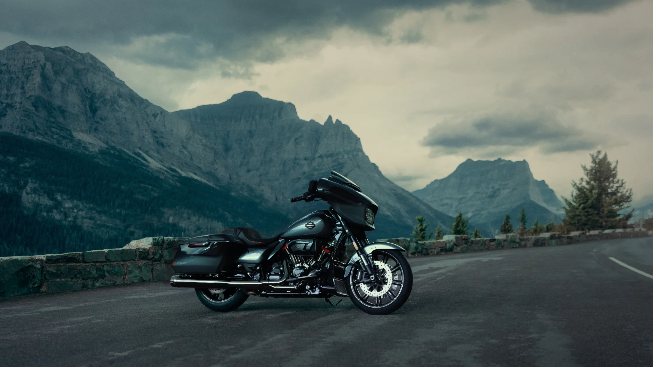 2025 Harley-Davidson CVO Street Glide cruiser parked on mountain road under cloudy skies.