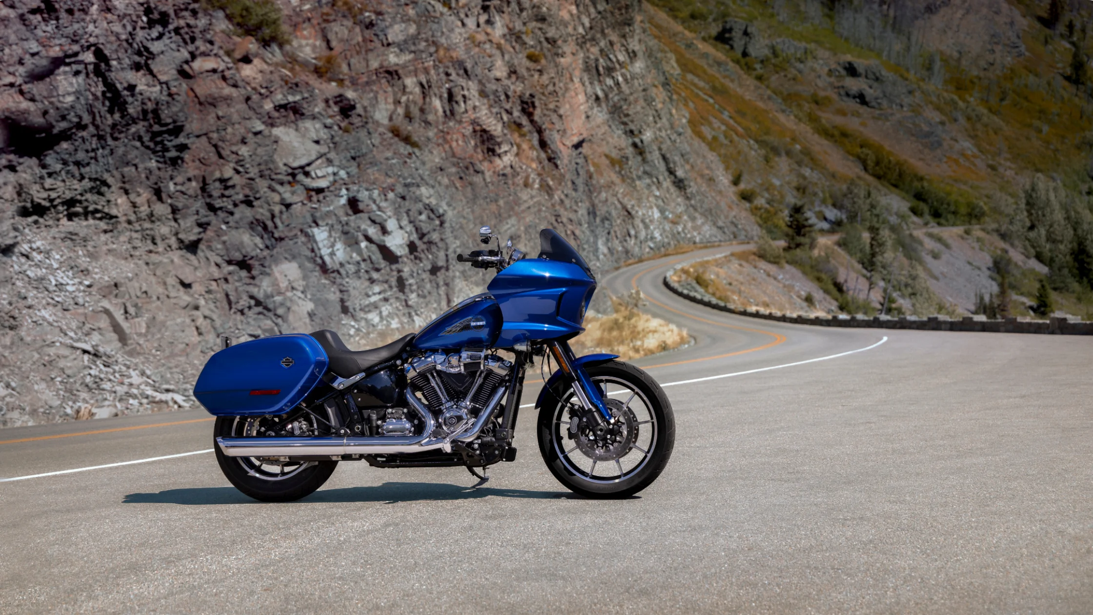 2025 Harley-Davidson Low Rider ST in blue on winding canyon road showcasing sleek performance
