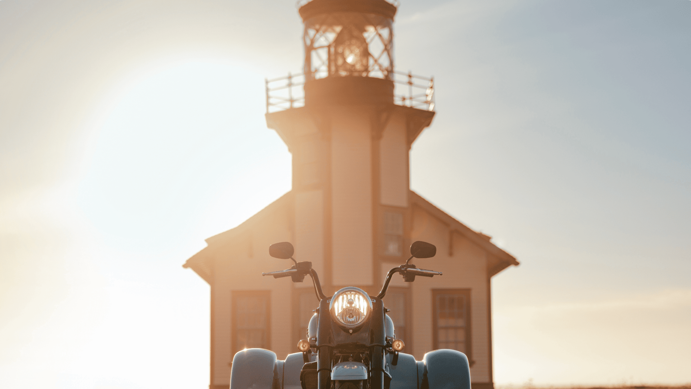 2025 Harley-Davidson Freewheeler trike parked near lighthouse under warm sunset glow