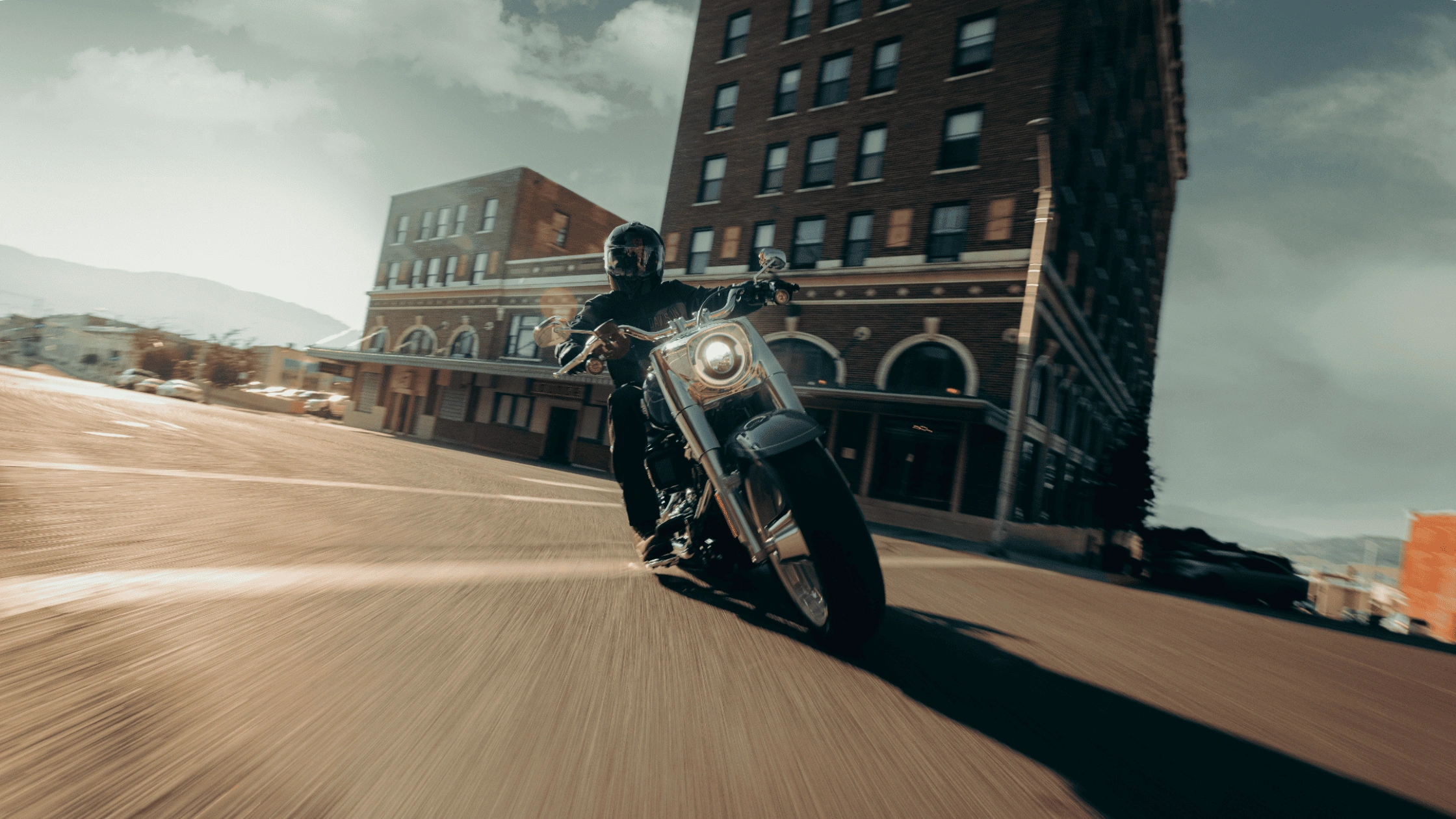 2025 Harley-Davidson Fat Boy riding through a city intersection, showcasing its iconic solid disc wheels and bold stance.