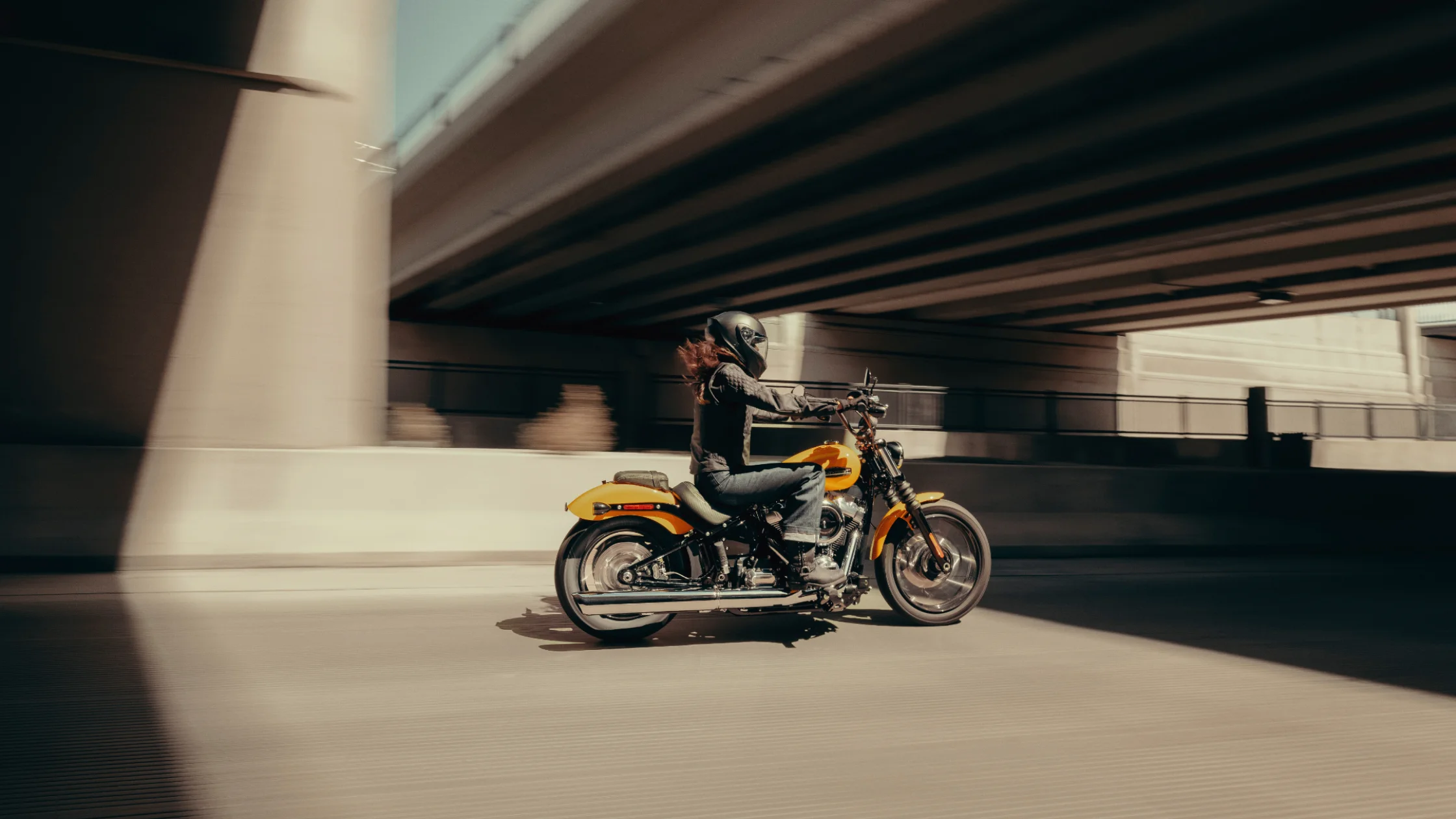 2025 Harley-Davidson® Street Bob® in motion under city bridge with low sunlight and shadow play