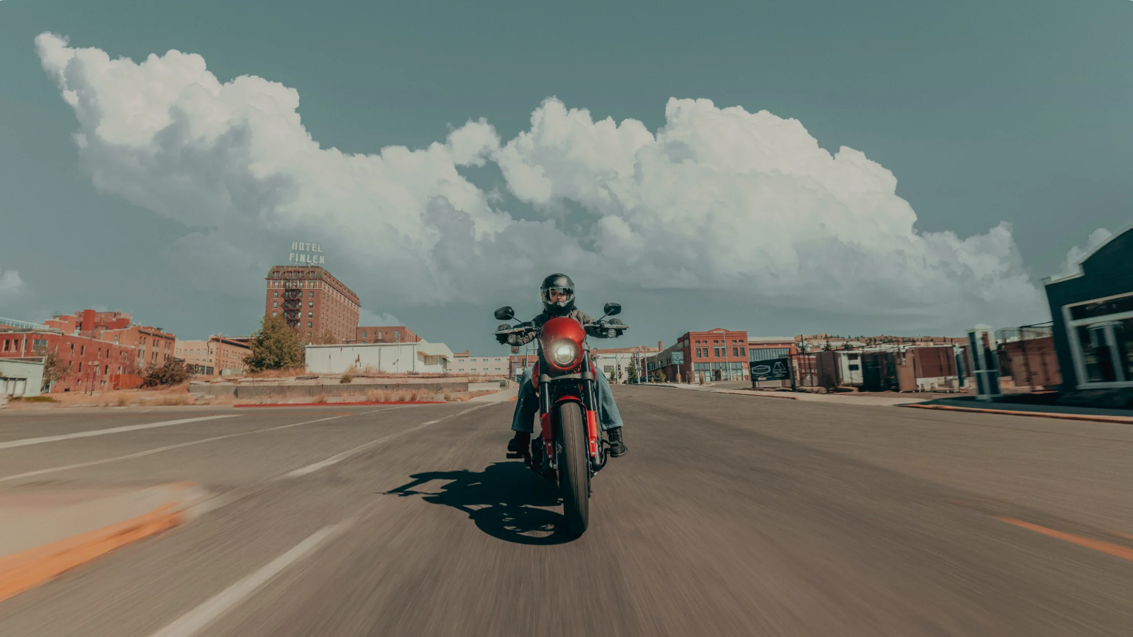 Rider on a red 2025 Harley-Davidson Low Rider S cruising through an urban street with vintage buildings.