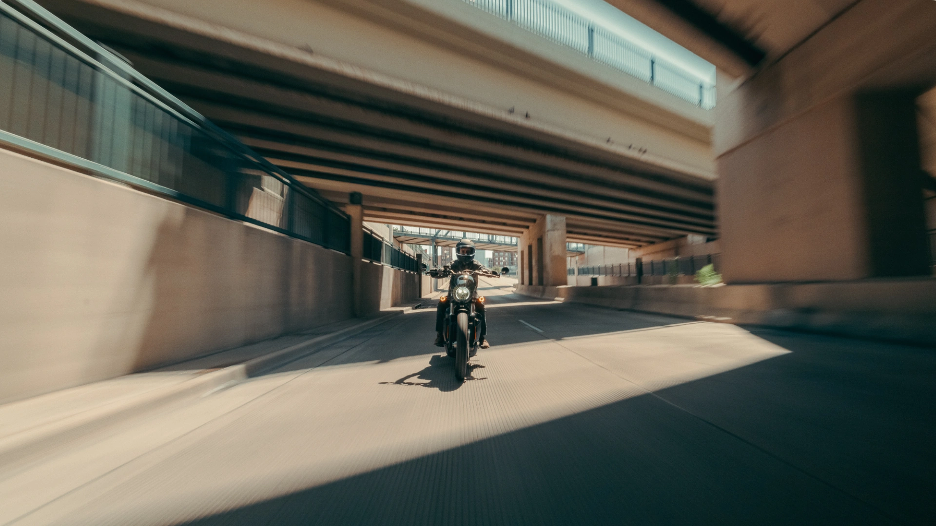 Rider cruising a 2025 Harley-Davidson® Nightster® Special under a bridge, showcasing its sleek urban design.