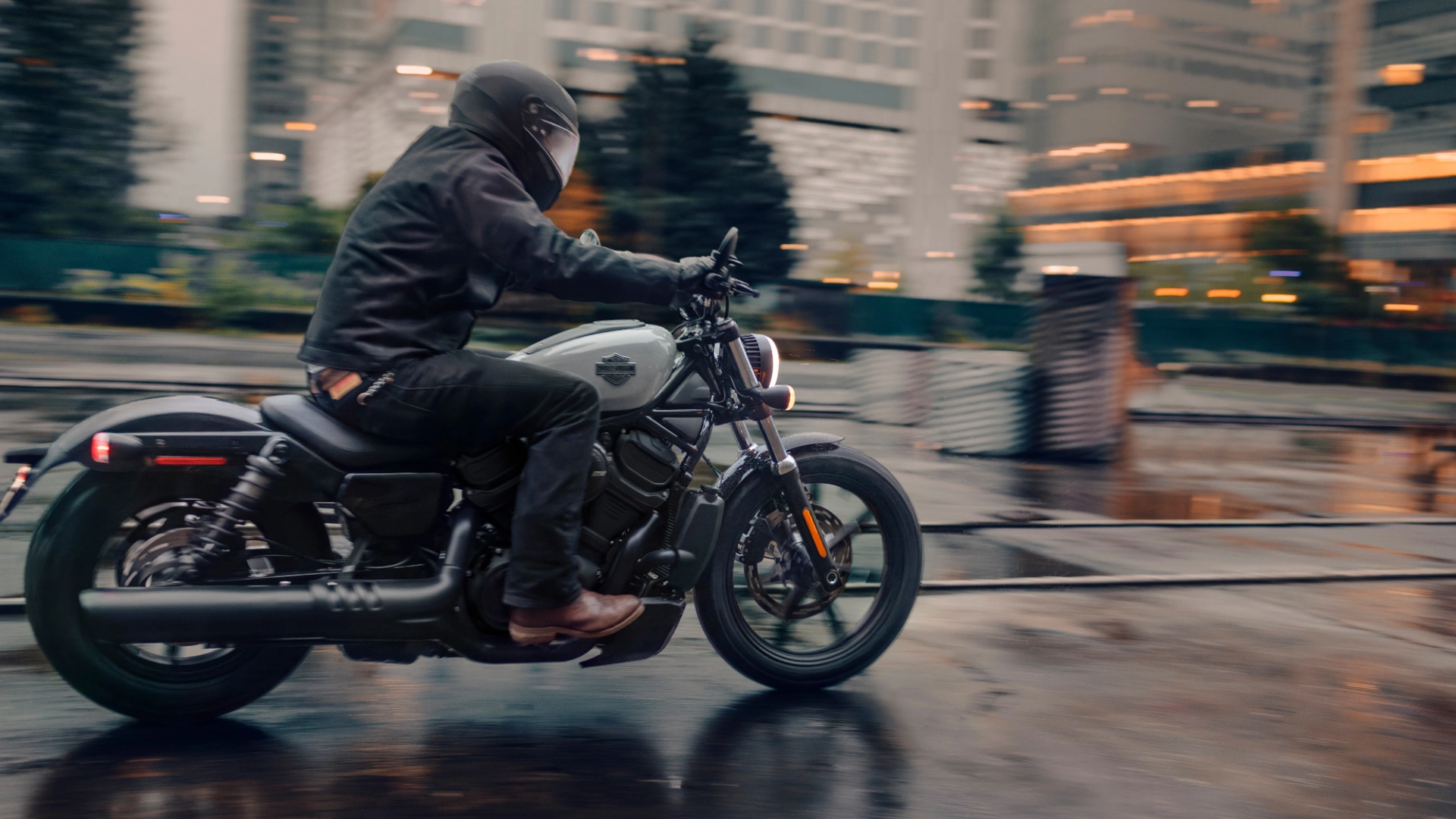 Side view of a 2025 Harley-Davidson® Nightster® in motion on a wet city street, emphasizing agility and modern styling.