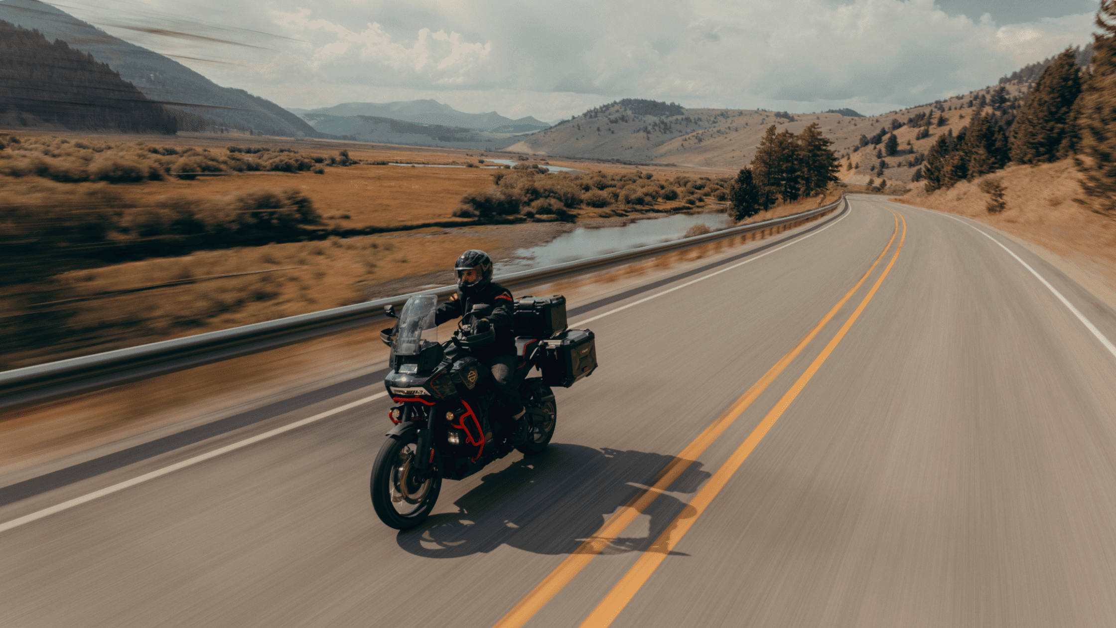 A rider cruising the scenic countryside on the 2025 Harley-Davidson® CVO™ Pan America® adventure bike.