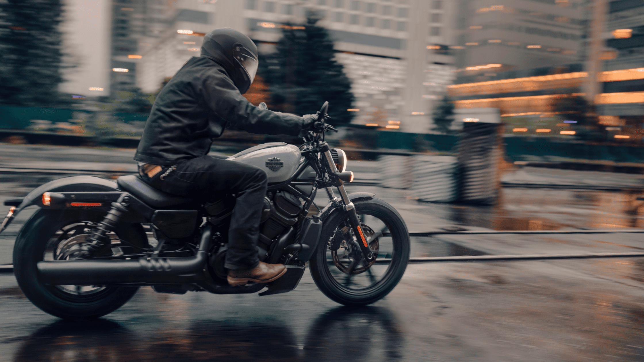 2025 Harley-Davidson Nightster riding through a wet city street with motion blur in low-light setting