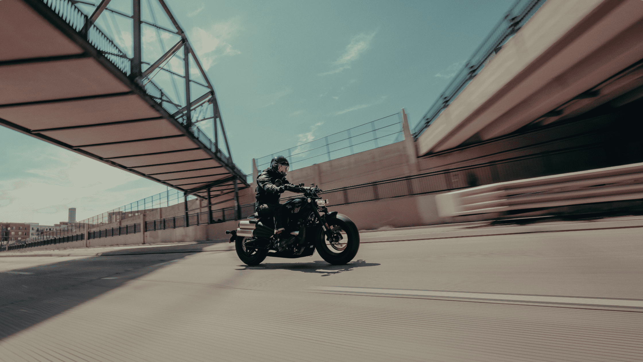 2025 Harley-Davidson® Sportster® S motorcycle riding beneath a bridge, showcasing its aggressive design, low profile, and Revolution® Max 1250T power.
