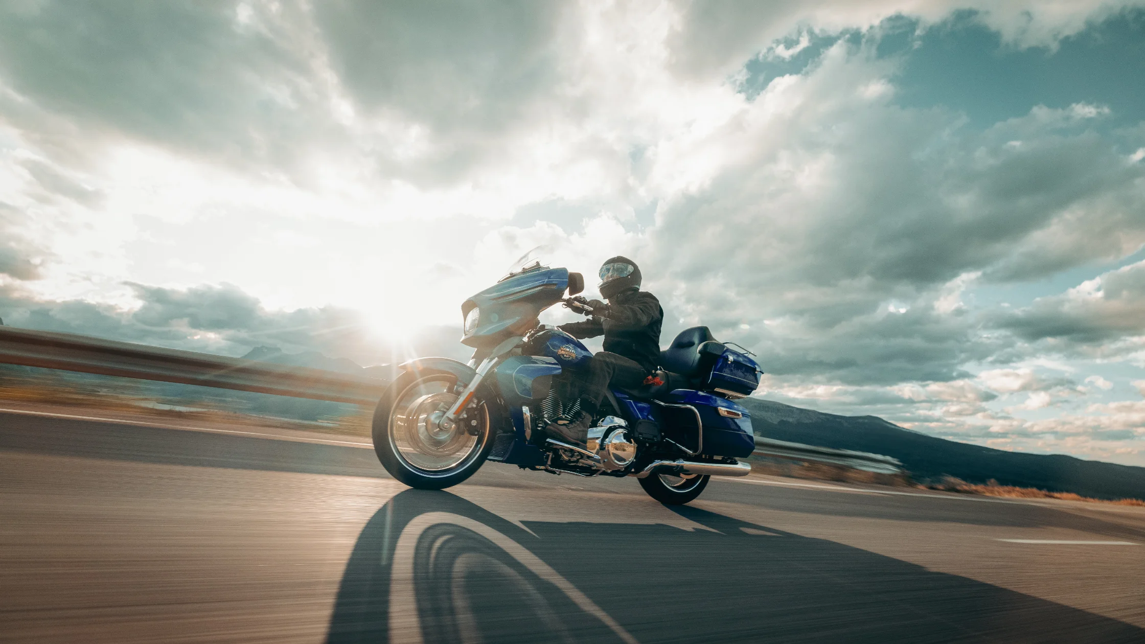 2025 H-D Street Glide Ultra cruising highway with full touring setup and rider silhouetted against sky