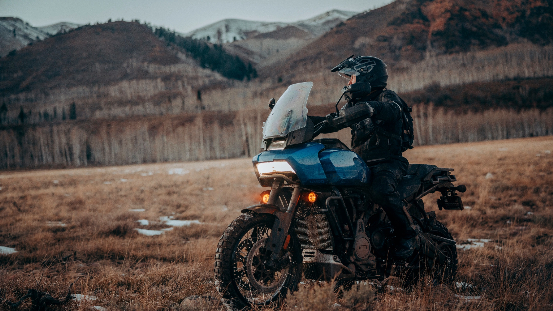 Adventure rider on a 2025 Pan America 1250 Special parked in rugged terrain with mountain backdrop.
