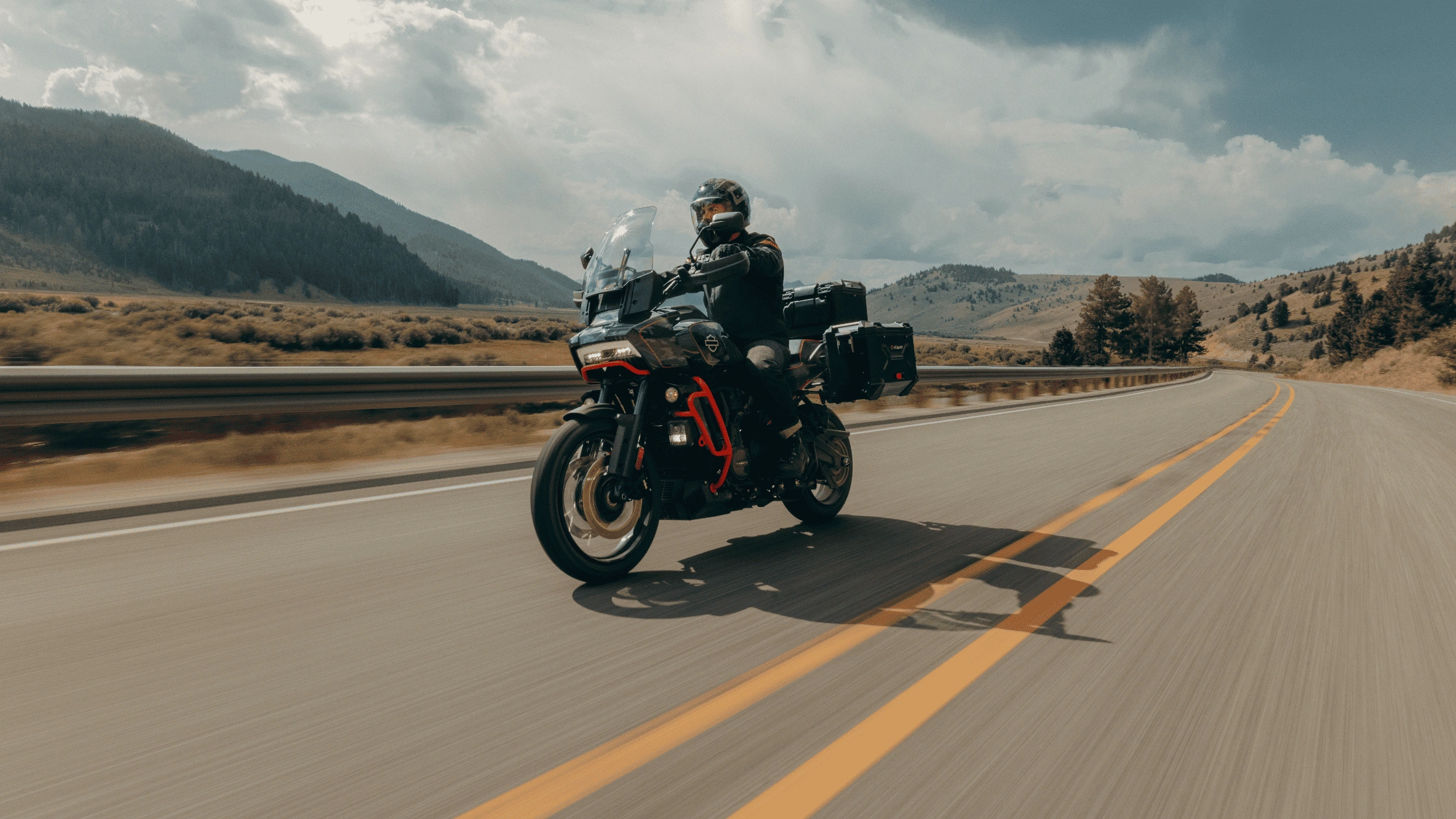 Motorcyclist riding the 2025 Harley-Davidson CVO™ Pan America® on an open scenic highway, built for adventure riders near Bentonville.
