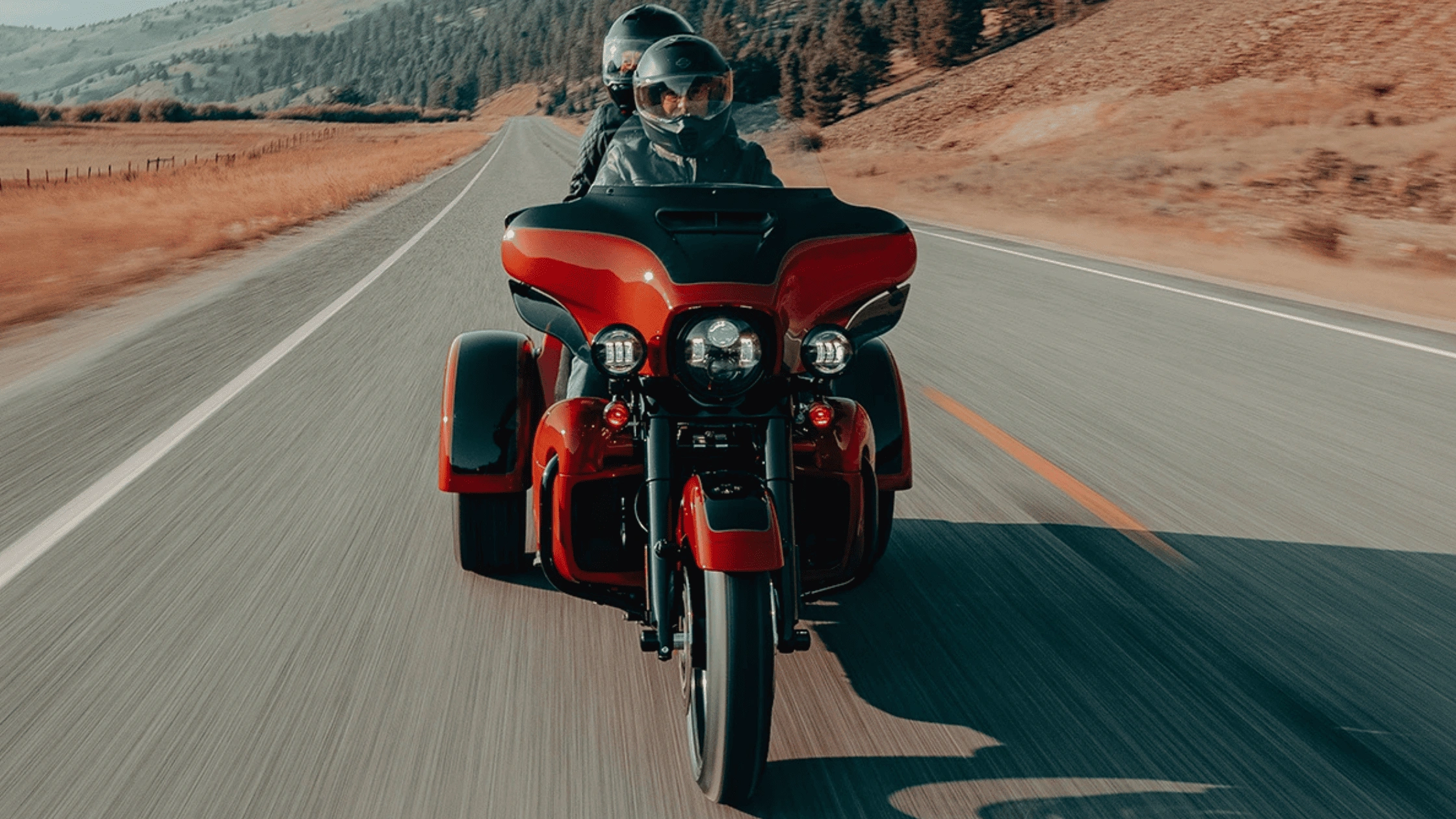2025 Harley-Davidson® Tri Glide® Ultra touring with two riders on open highway in bright daylight.