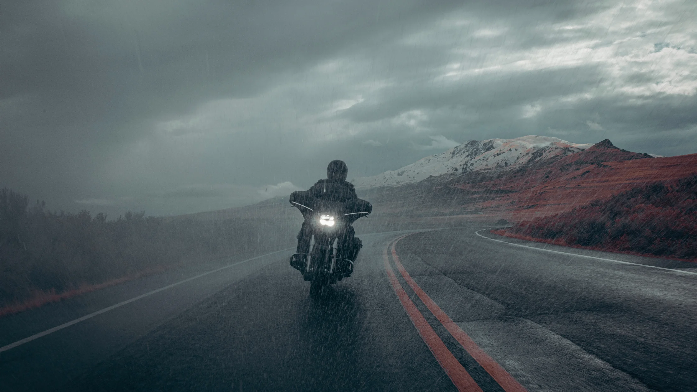 2025 H-D® Street Glide® riding through heavy rain on a mountain road with stormy skies overhead