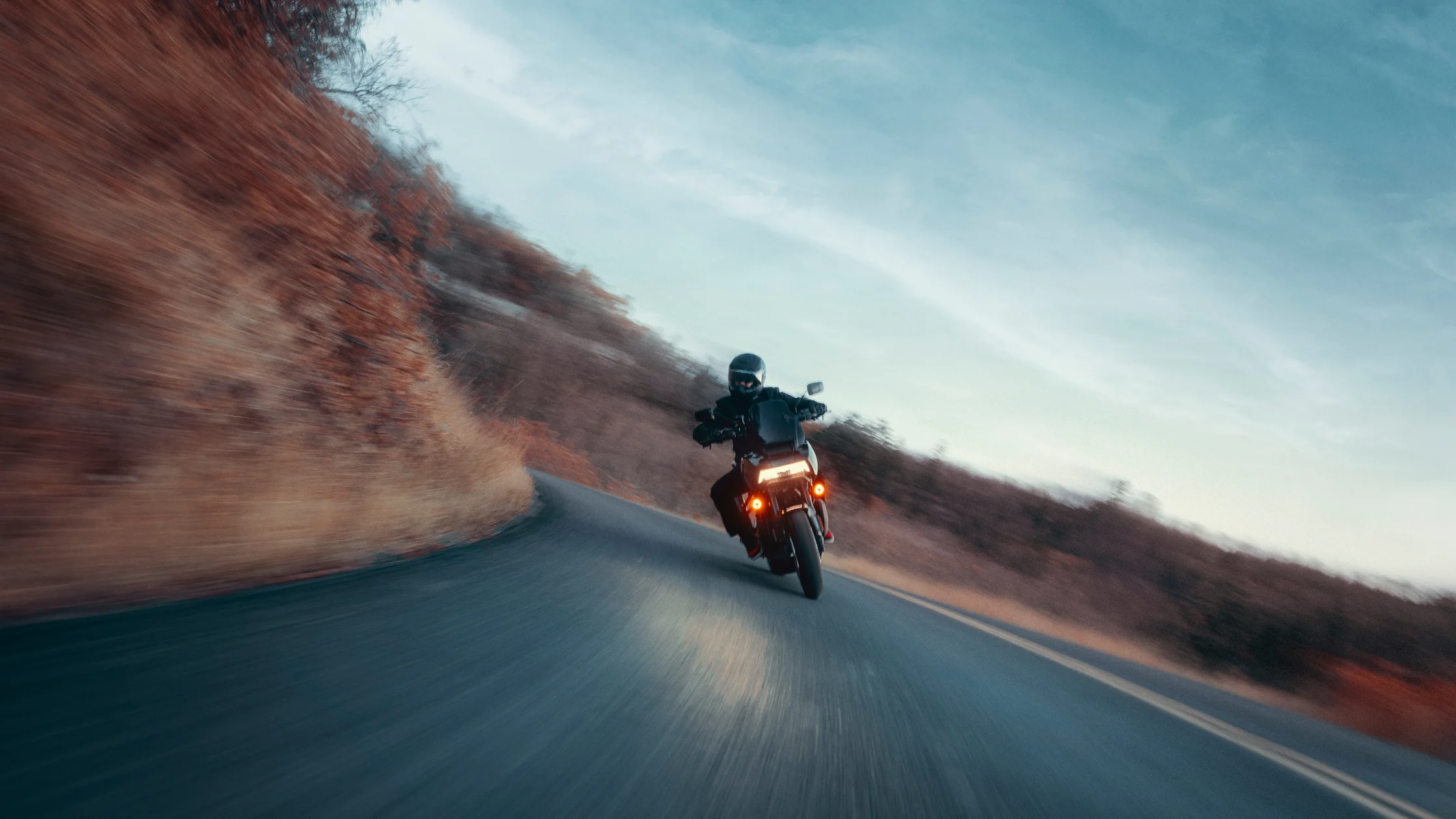 2025 Pan America 1250 ST leaning into a high-speed corner on a winding mountain road.