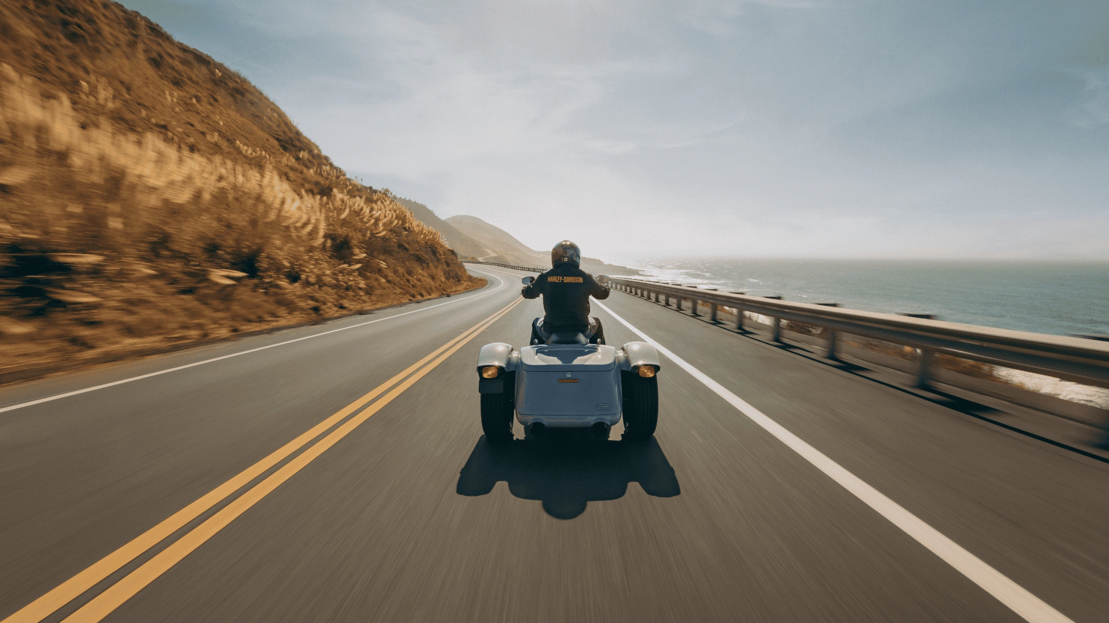 Rider cruising a 2025 Harley-Davidson Freewheeler along a coastal highway, showing stability and power ideal for Sunrise commuters.