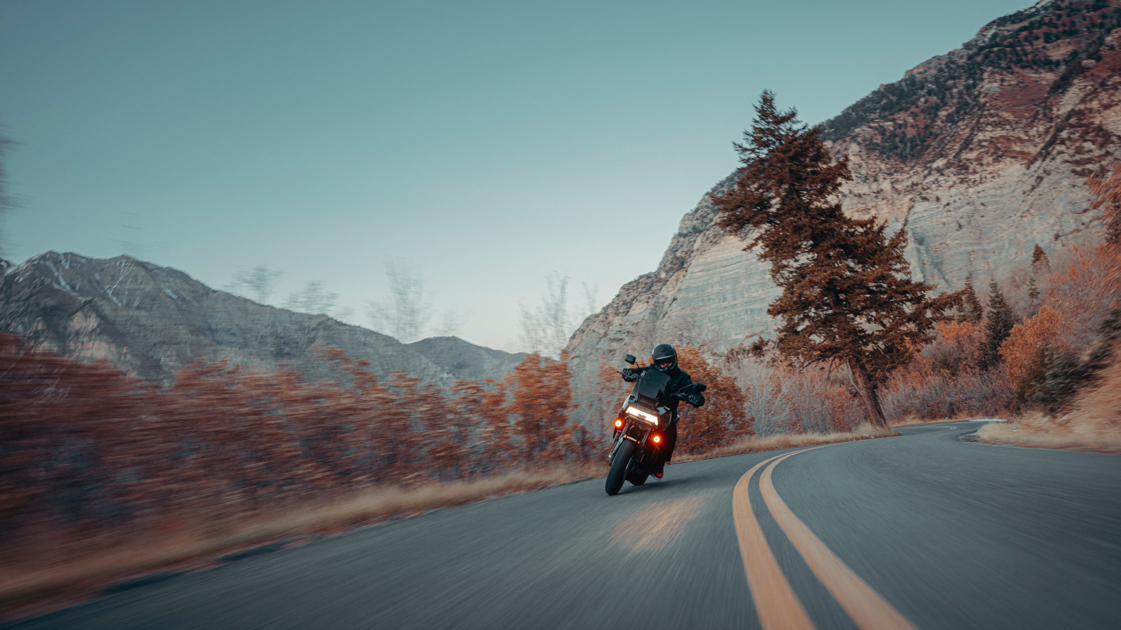 2025 Harley-Davidson® Pan America® 1250 ST cornering through a mountain road surrounded by autumn scenery.