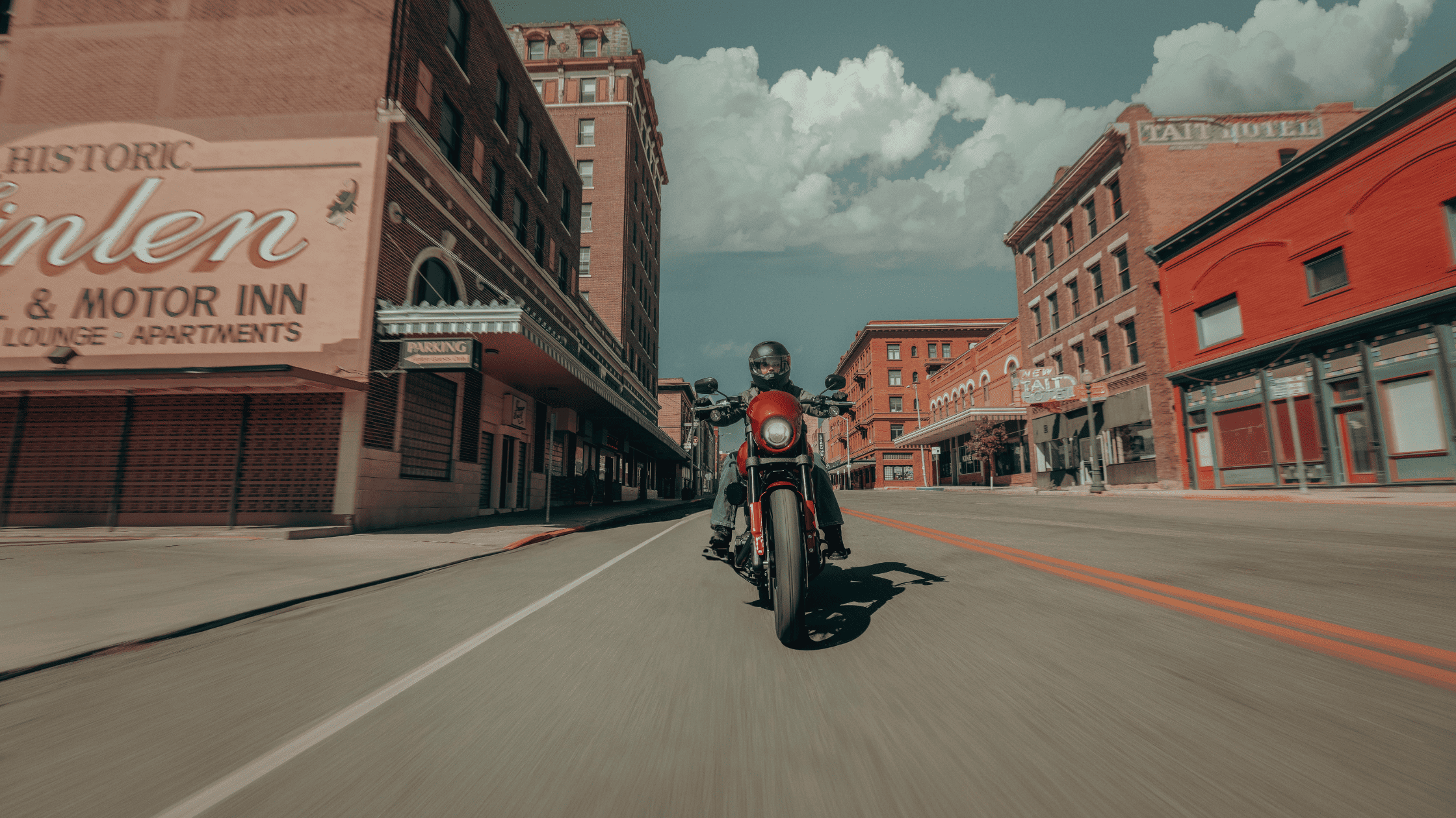 Front view of a 2025 Harley-Davidson® Low Rider® S riding through a historic downtown area under bright daylight.