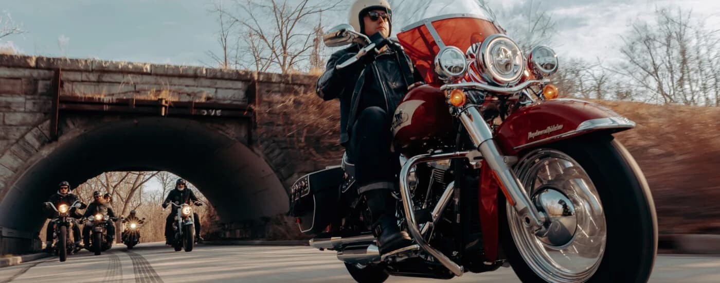 A red 2024 Harley-Davidson Hydra Glide Revival is driving after leaving a Harley-Davidson Dealer nea…