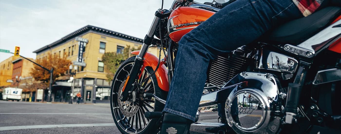 An orange 2023 Harley-Davidson Breakout is shown while stopped at a traffic light.