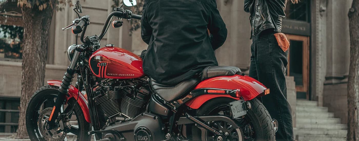 Two people are shown standing next to a red Harley-Davidson Street Bob 114.