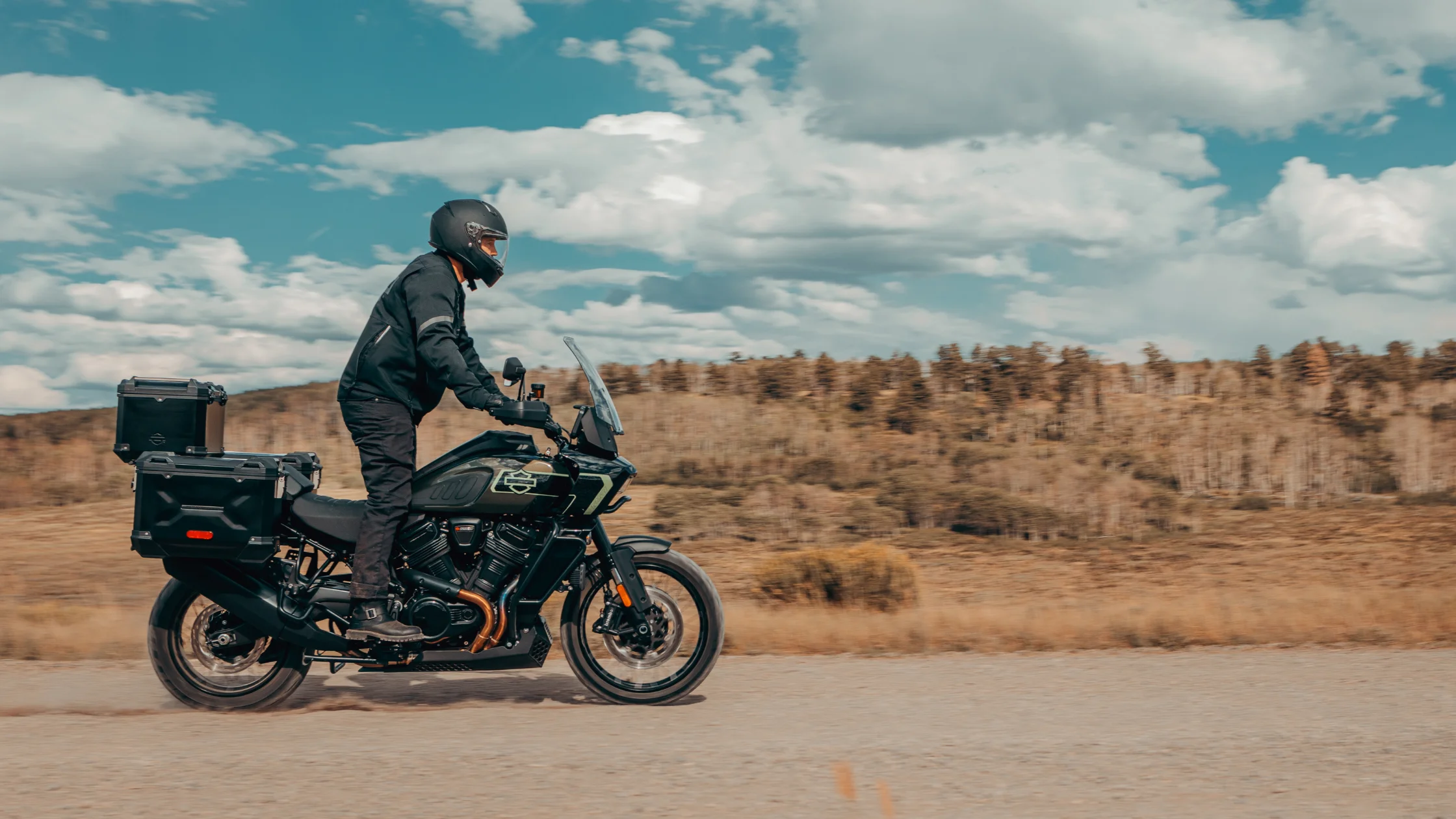 2026 Harley-Davidson® Pan America® 1250 Limited adventure bike riding on gravel road with touring luggage.
