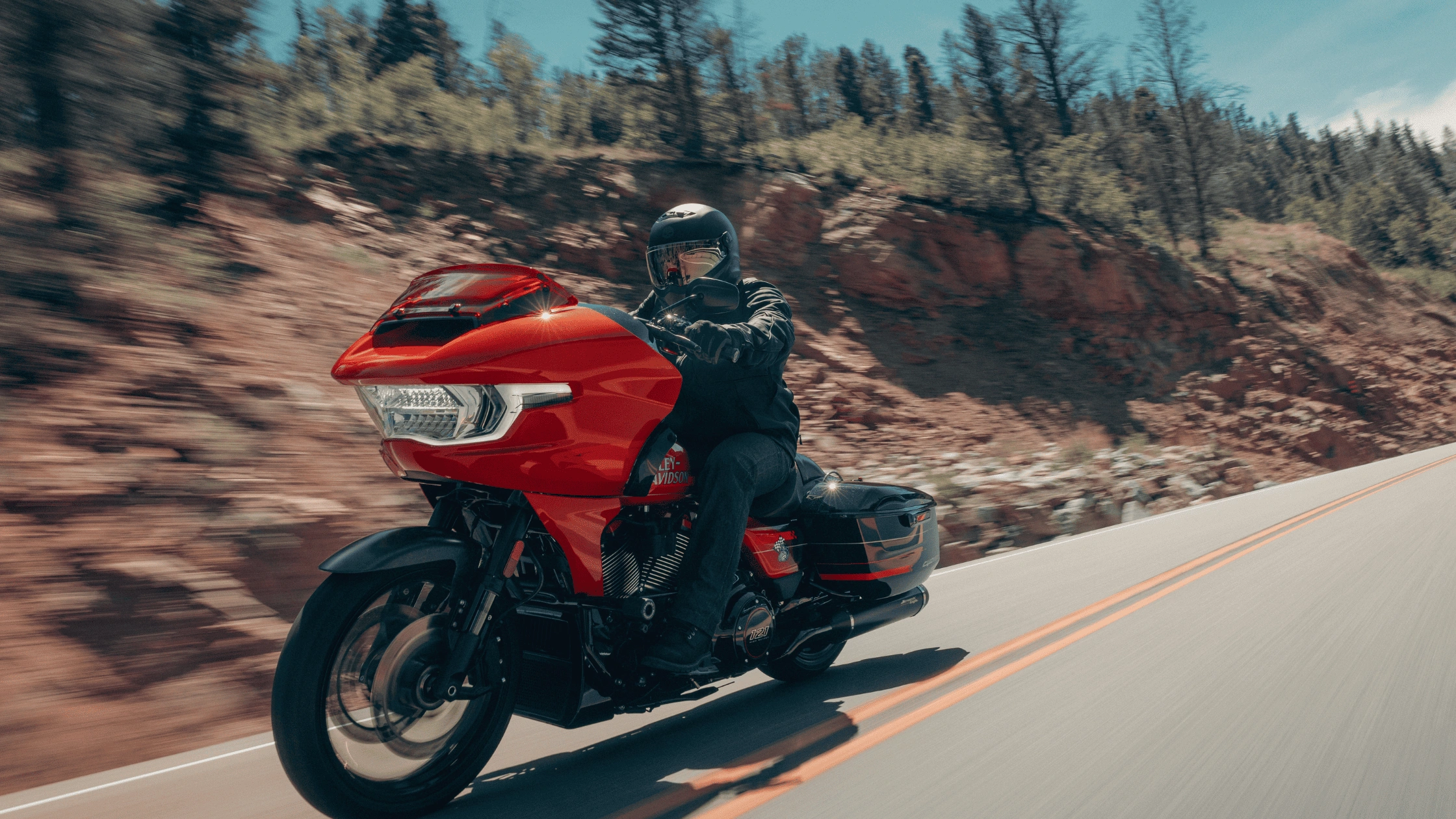 2026 Harley-Davidson CVO Road Glide ST ridden on a scenic mountain road, highlighting aggressive fairing design and performance-focused touring style.