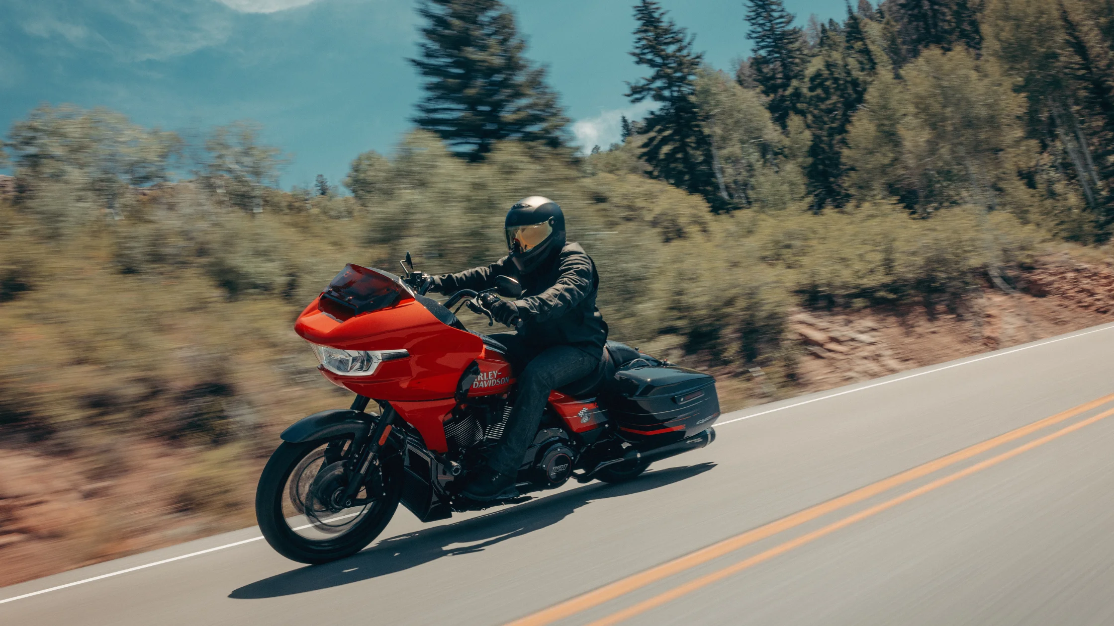 Rider on a red 2026 Harley-Davidson® CVO™ Road Glide® ST cruising a winding mountain road
