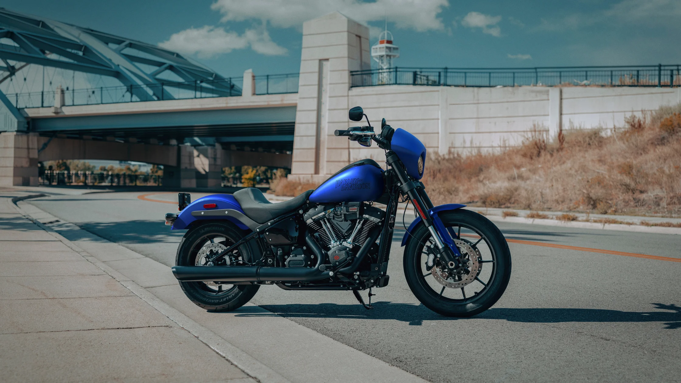 2026 Harley-Davidson® Low Rider® S in blue displayed roadside beneath an urban bridge structure
