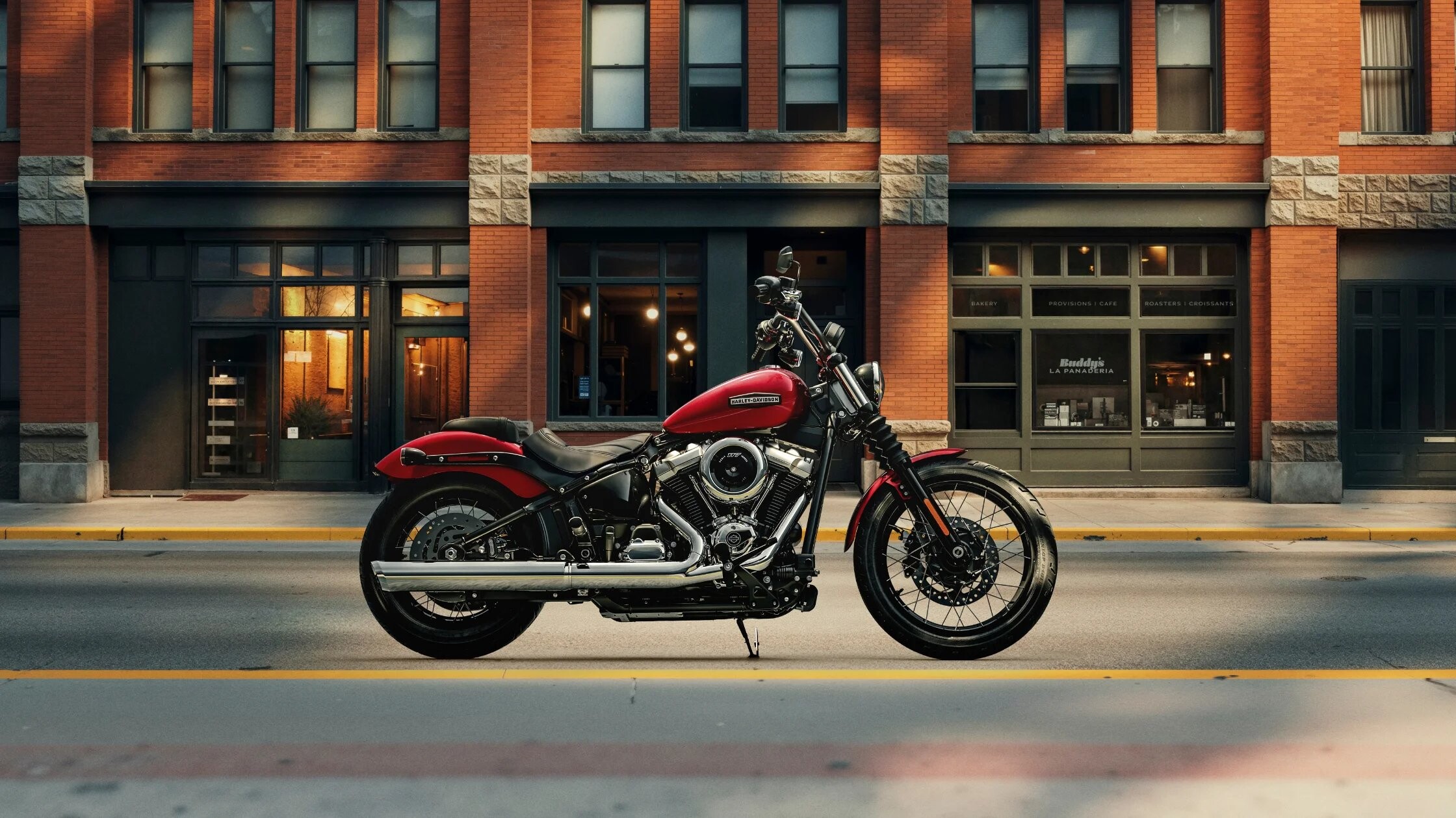 2026 Harley-Davidson® Street Bob® red cruiser motorcycle parked in front of brick building in city setting.