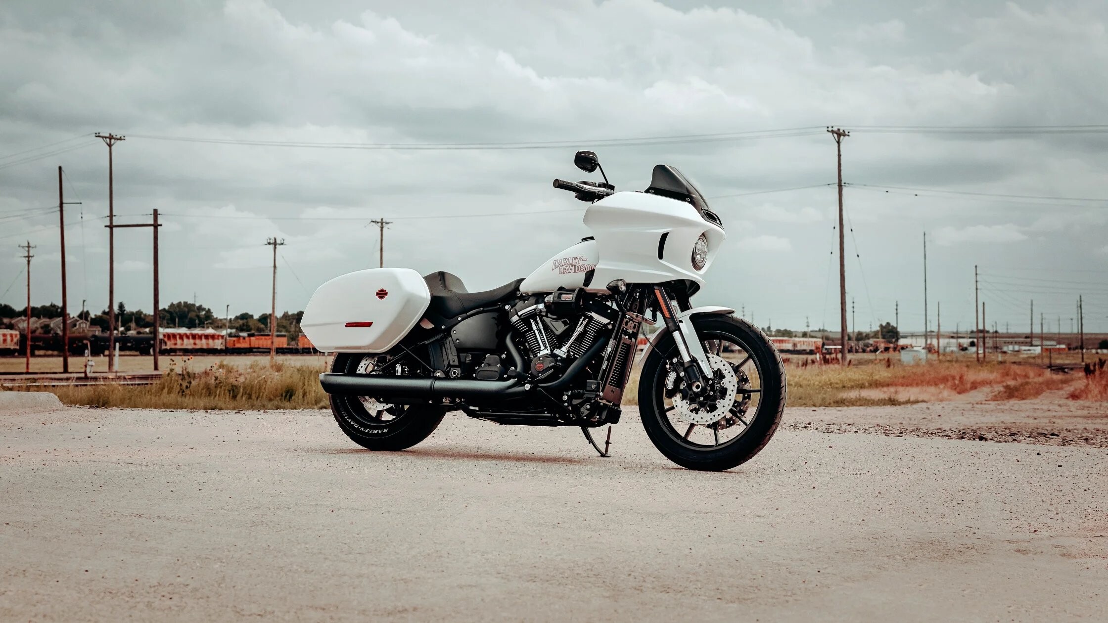 2026 Harley-Davidson® Low Rider® ST white performance touring motorcycle parked on gravel road with open landscape.