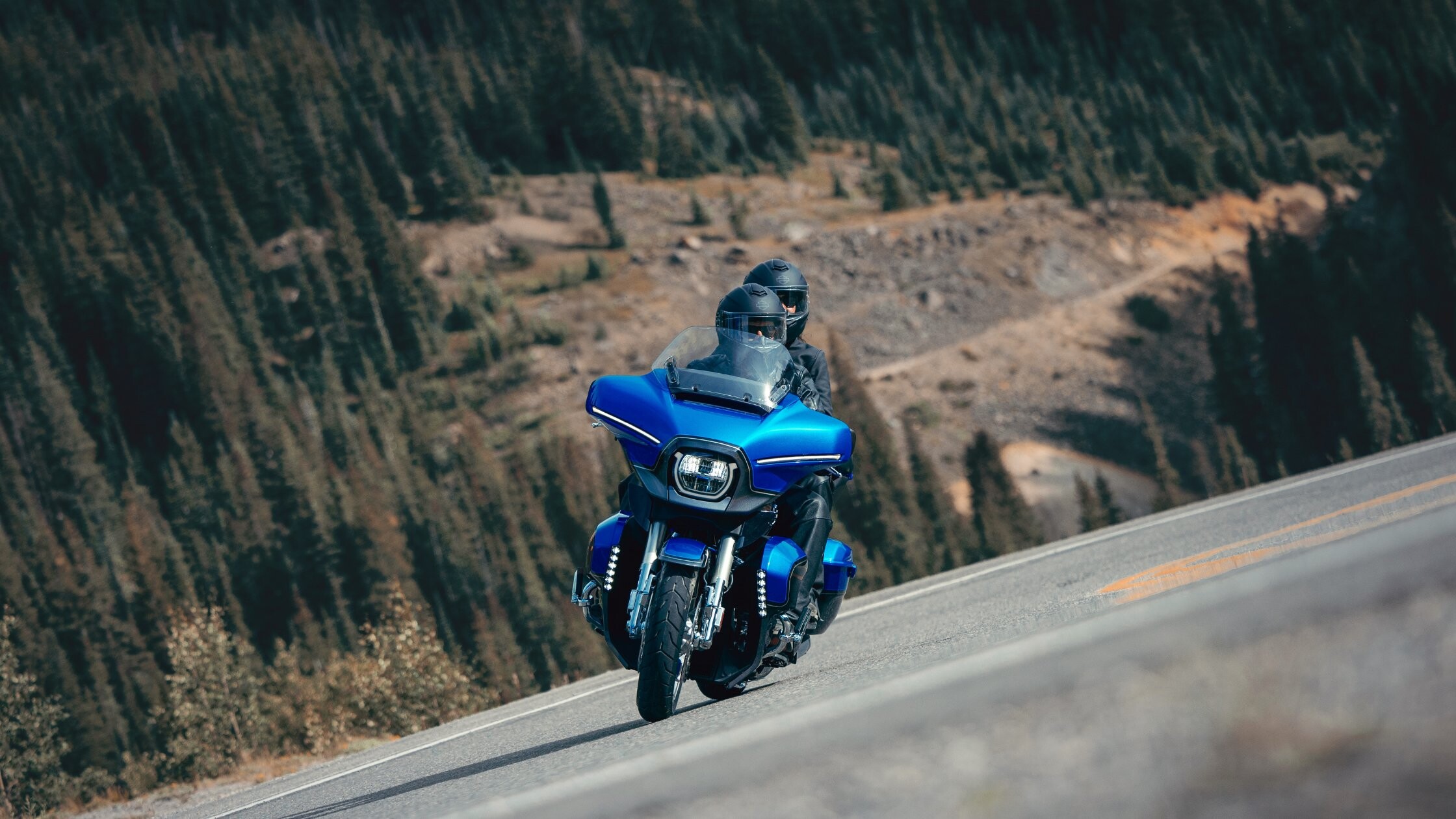 Blue 2026 H-D® CVO™ Street Glide® Limited riding on a mountain road with two riders