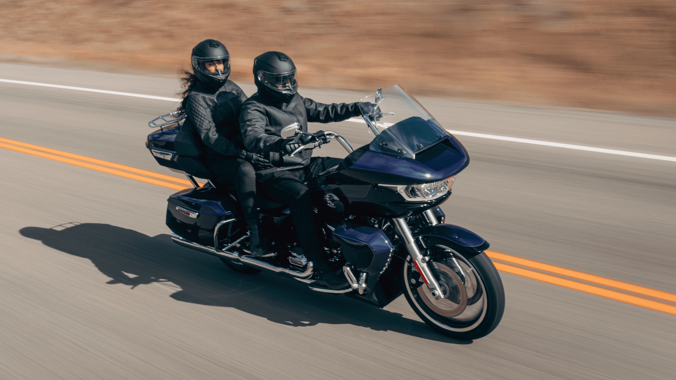 Two riders on a 2026 Harley-Davidson Road Glide Limited in dark blue touring an open highway, available in Baton Rouge LA