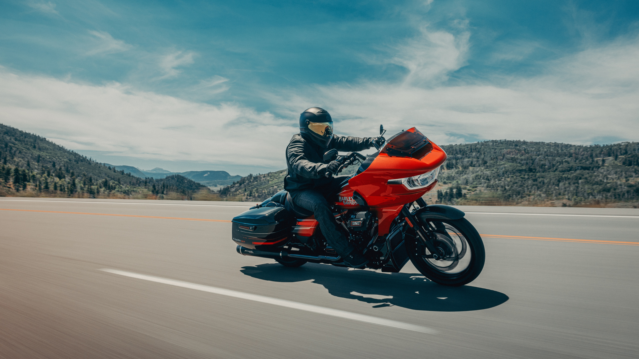 2026 CVO™ Road Glide® ST motorcycle riding on a highway with mountain scenery