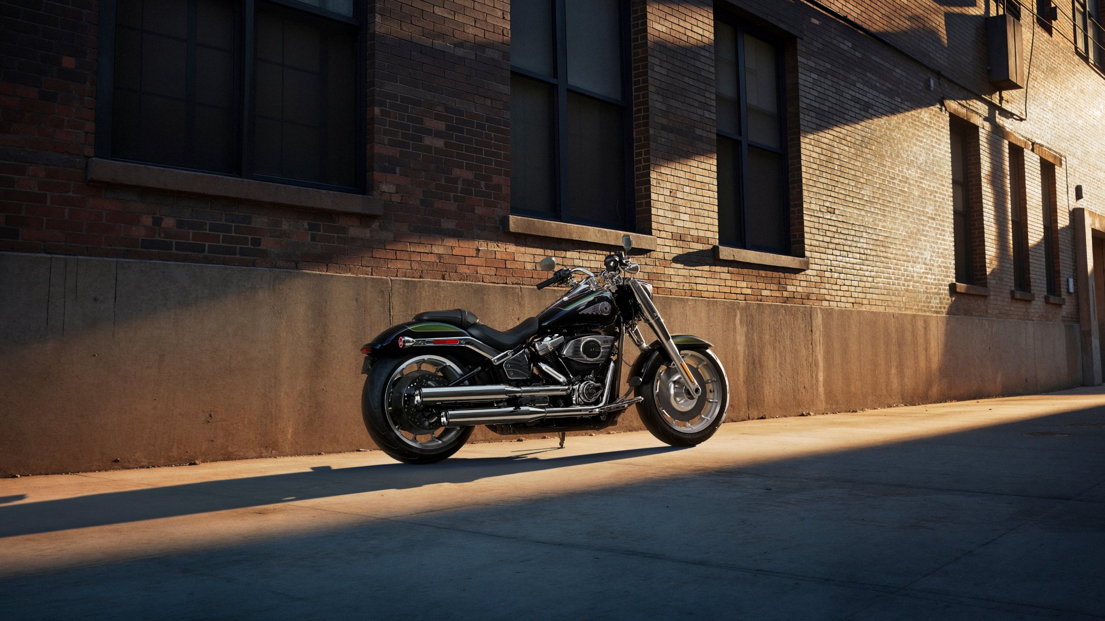 2026 Harley-Davidson® Fat Boy® motorcycle parked beside a brick building in warm evening light
