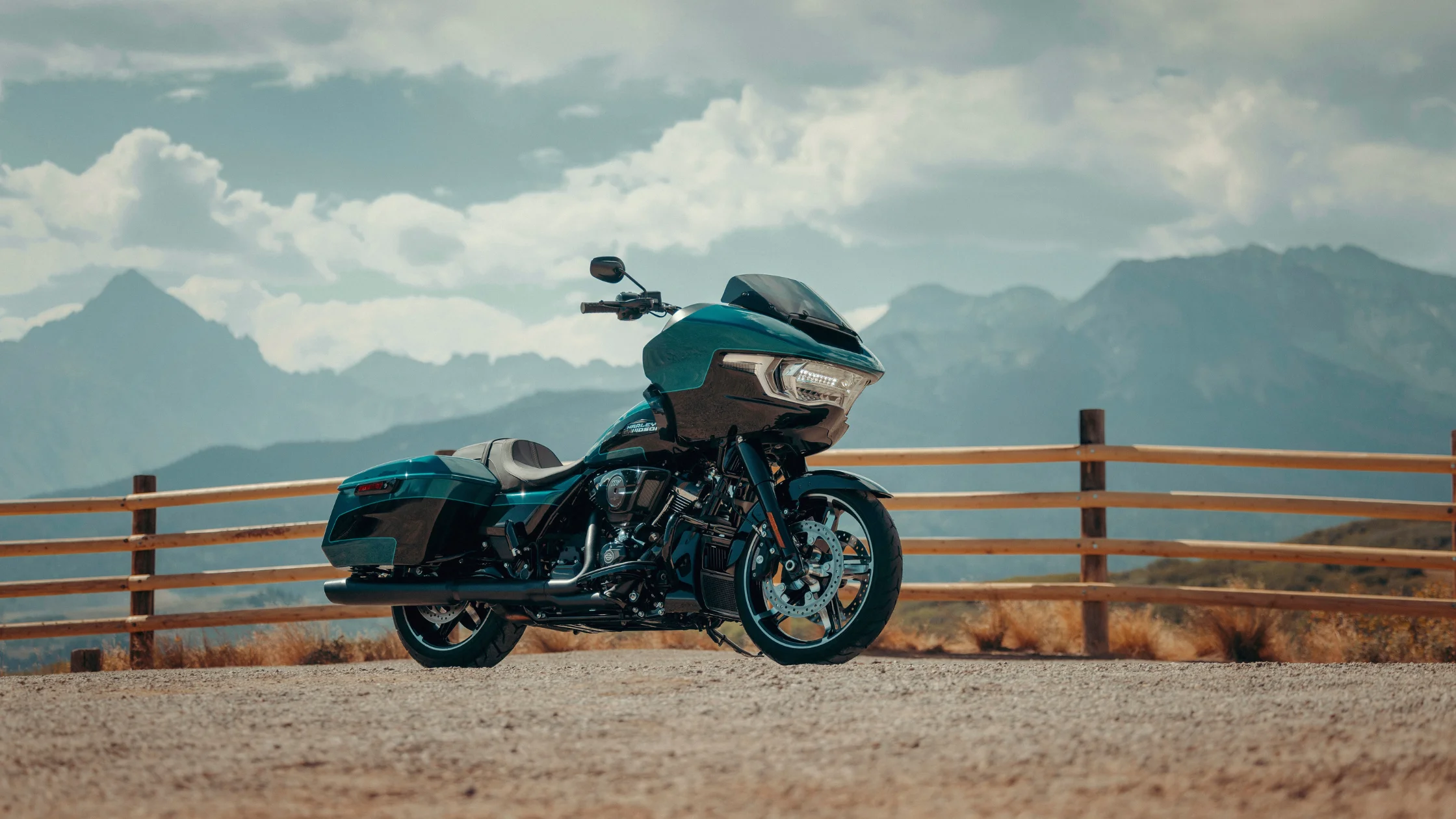 2026 Road Glide® teal touring motorcycle parked by mountain overlook with fairing and saddlebags.