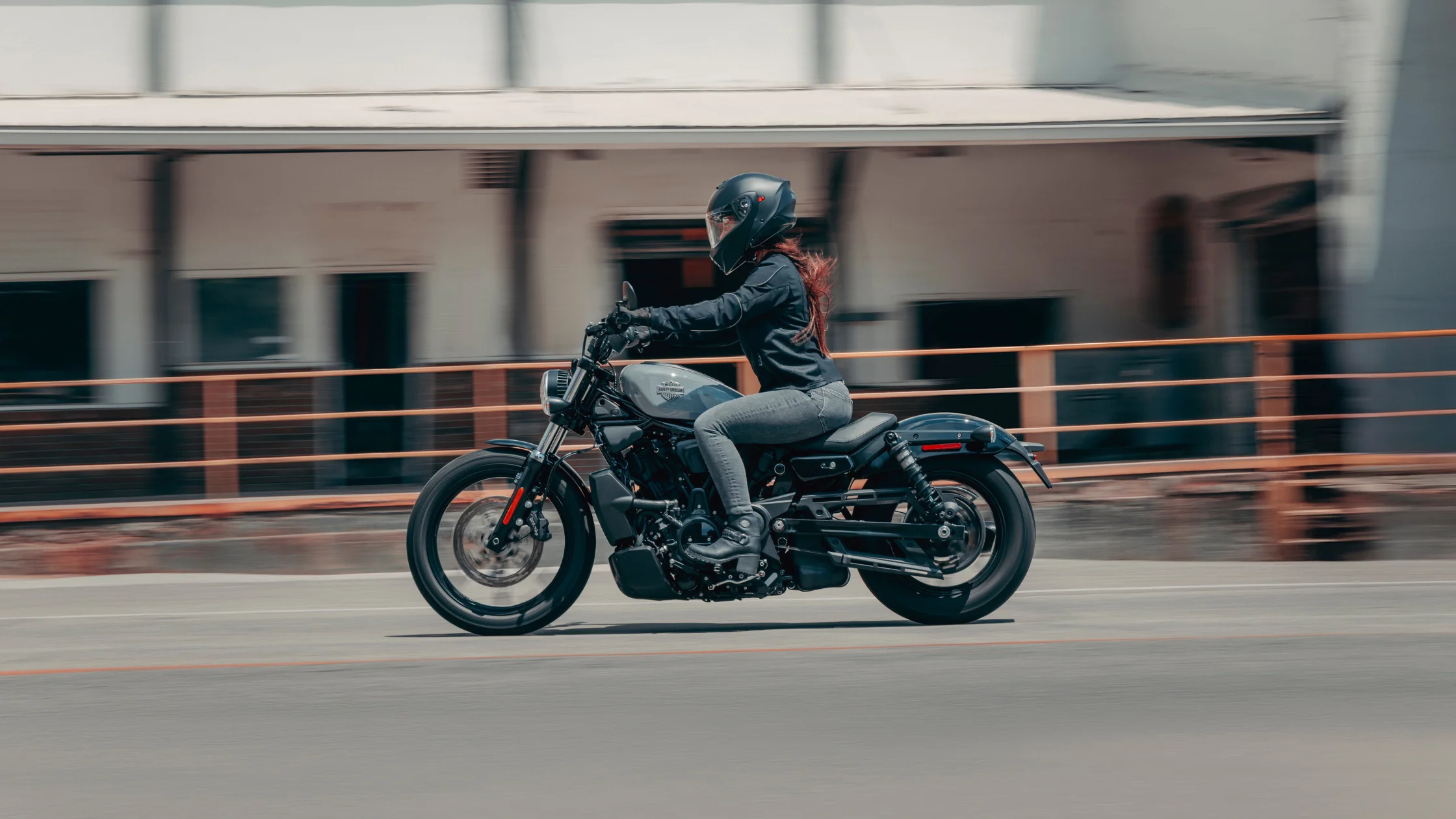 Rider on a 2026 H-D® Nightster® motorcycle cruising through an urban street